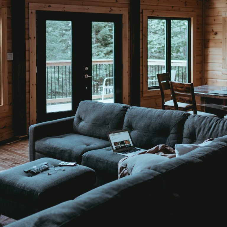 Gemütliches Wohnzimmer mit grauem Sofa, Fenster und Esstisch im Hintergrund trotz negativer Schufa