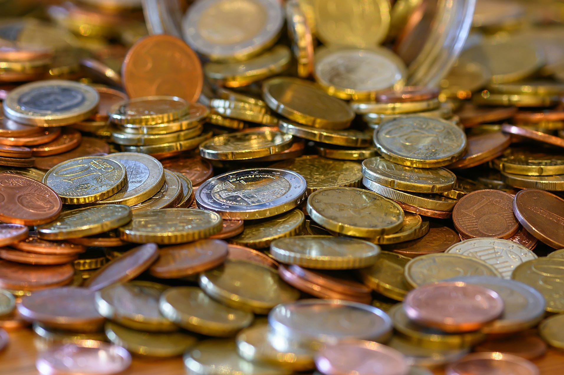 Eine Vielzahl von Münzen in verschiedenen Größen und Materialien auf einem Tisch. Kreditvergleich war positiv trotz negativer Schufa
