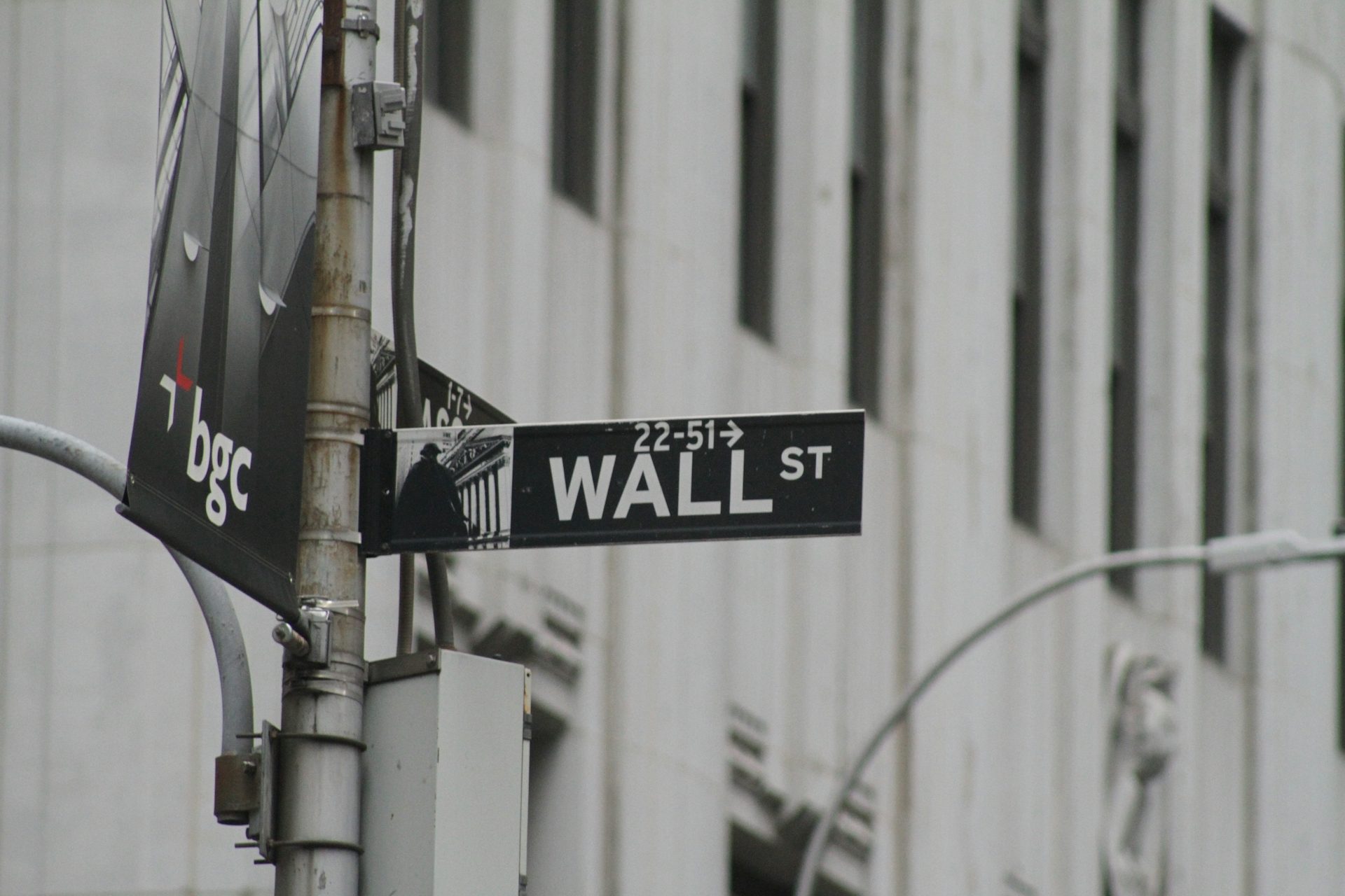 Straßenschild mit der Aufschrift "WALL ST" an einem urbanen Gebäude. Kredithandel